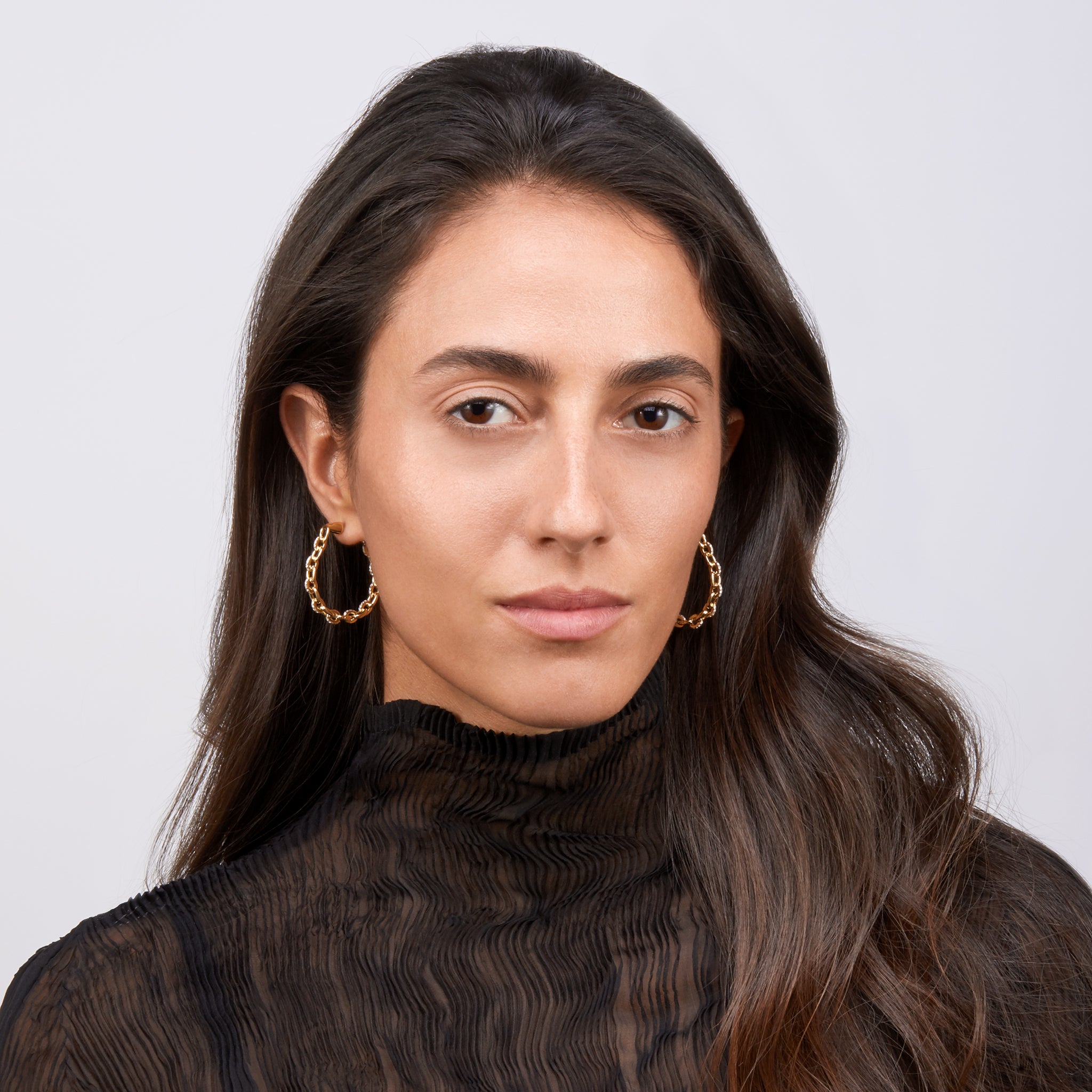 Model wearing the earrings against an off white background.