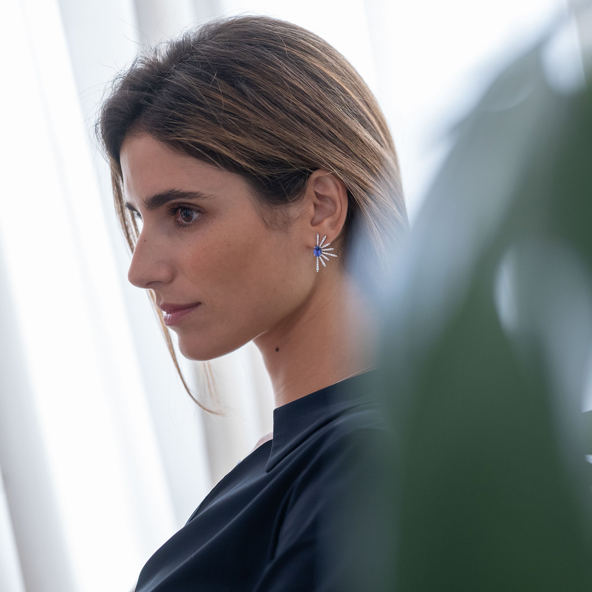 Diamond earrings with two elegant tanzanite ovals, depicted on a model.