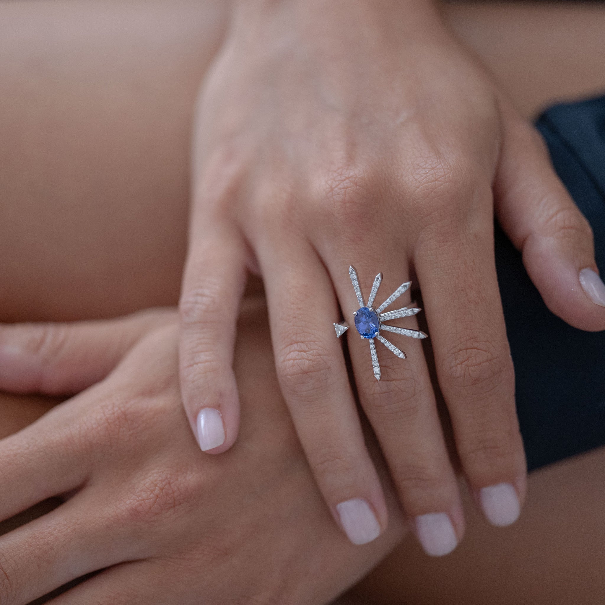 A striking ring featuring diamonds and an oval tanzanite, elegantly showcased on a hand model.