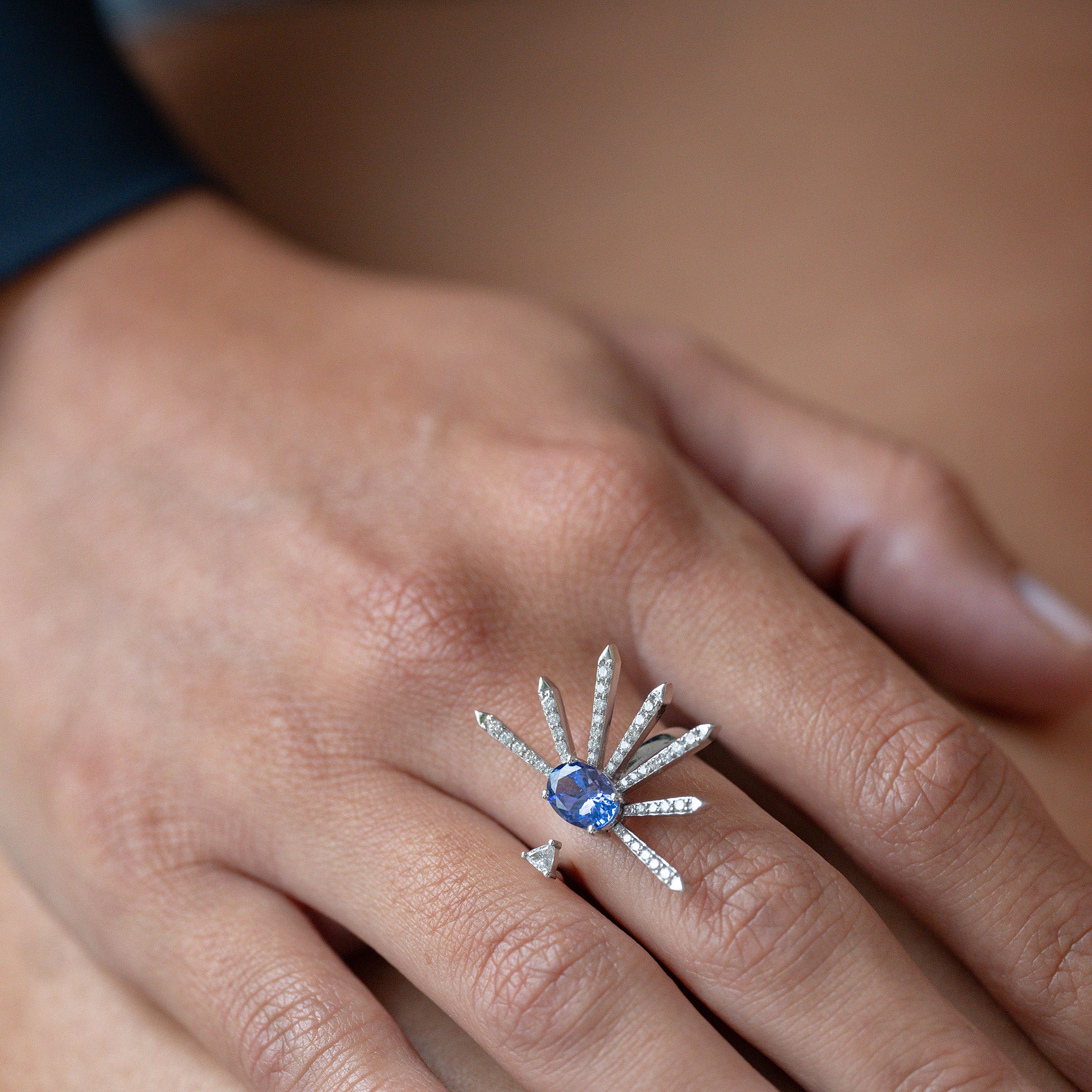 A striking ring featuring diamonds and an oval tanzanite, elegantly showcased on a hand model.
