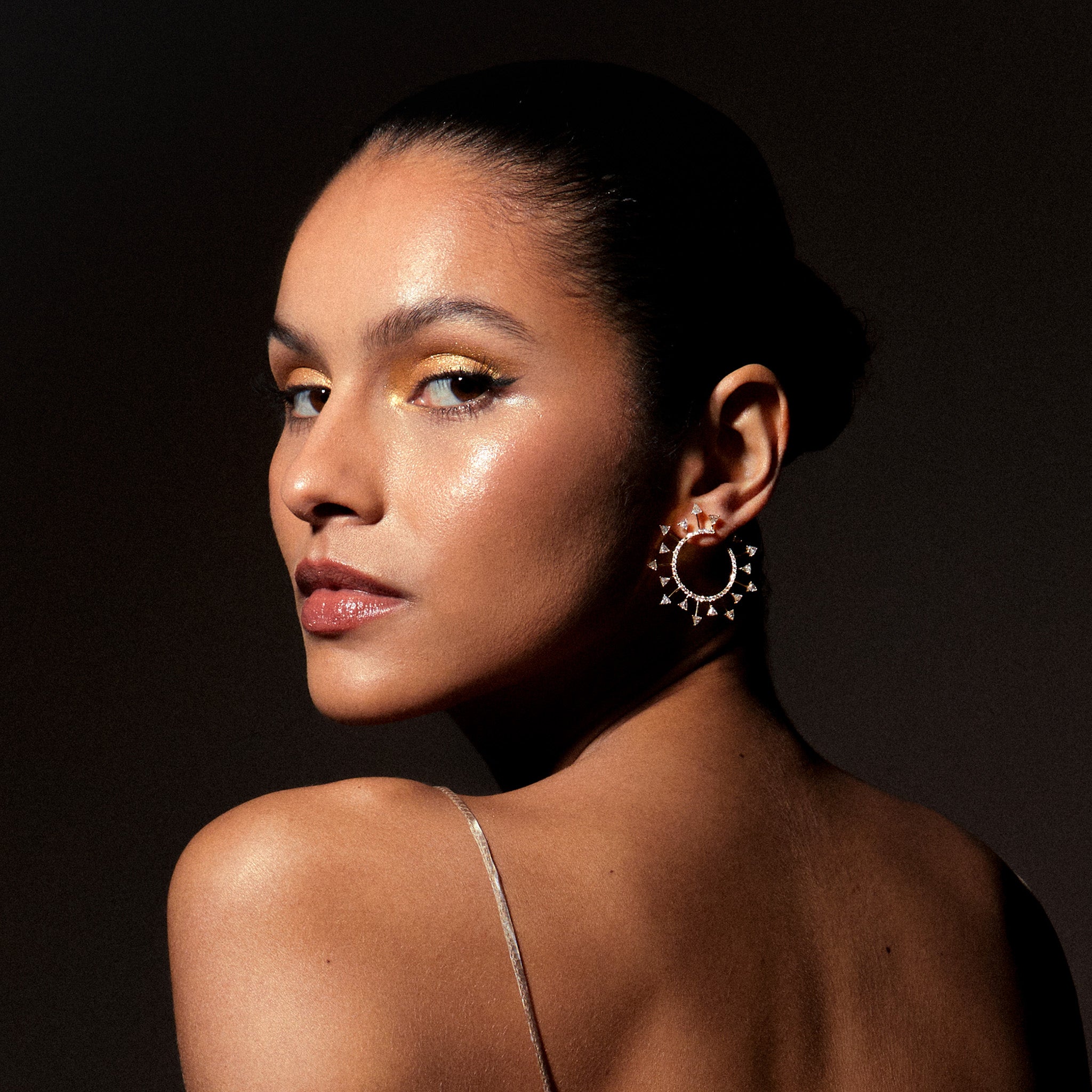 Yellow gold SunScape spiral hoop earrings with trillion-cut diamonds, depicted on model.