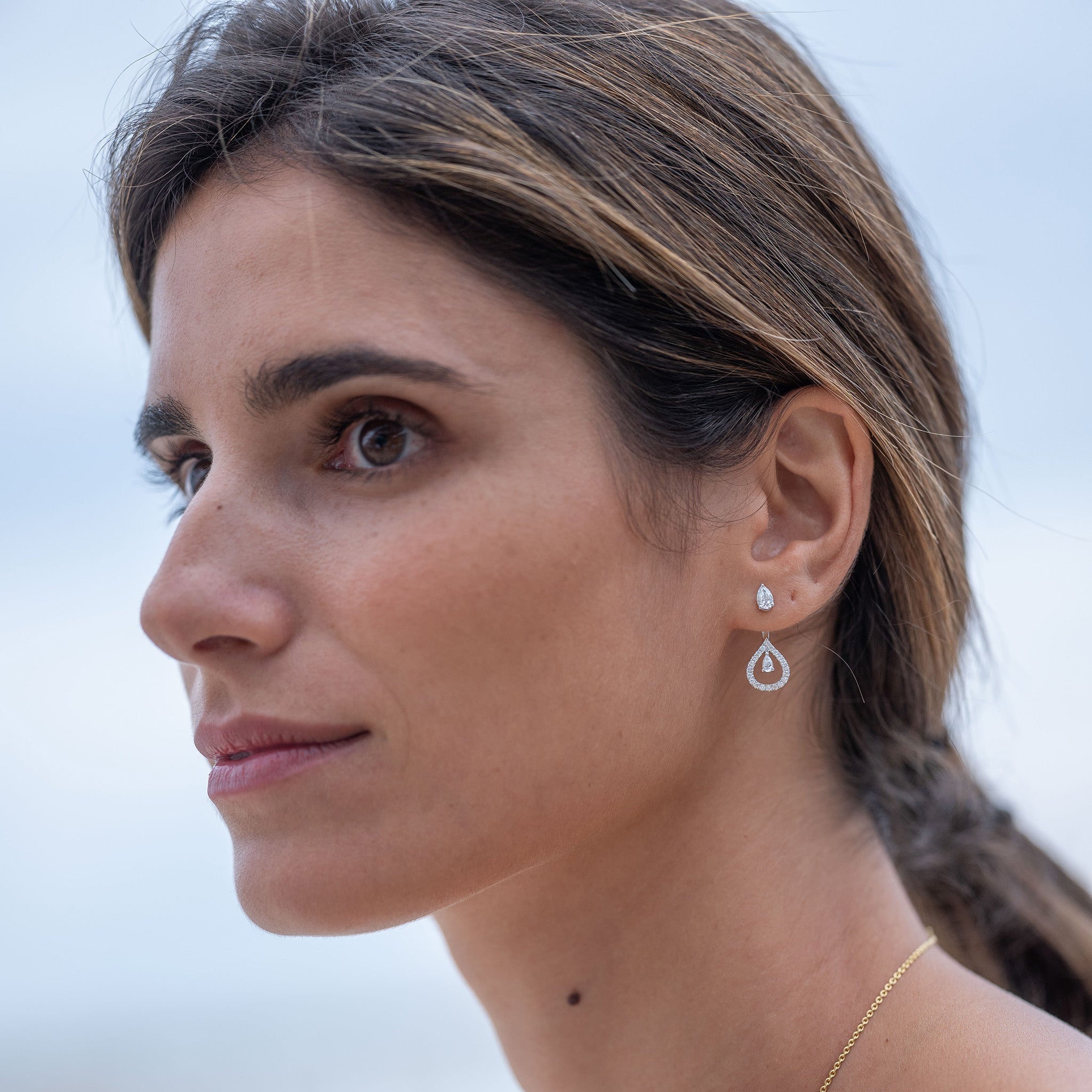 Venus single diamond earrings featuring a pear-shaped stud convertible design with additional extension diamonds, displayed on model.