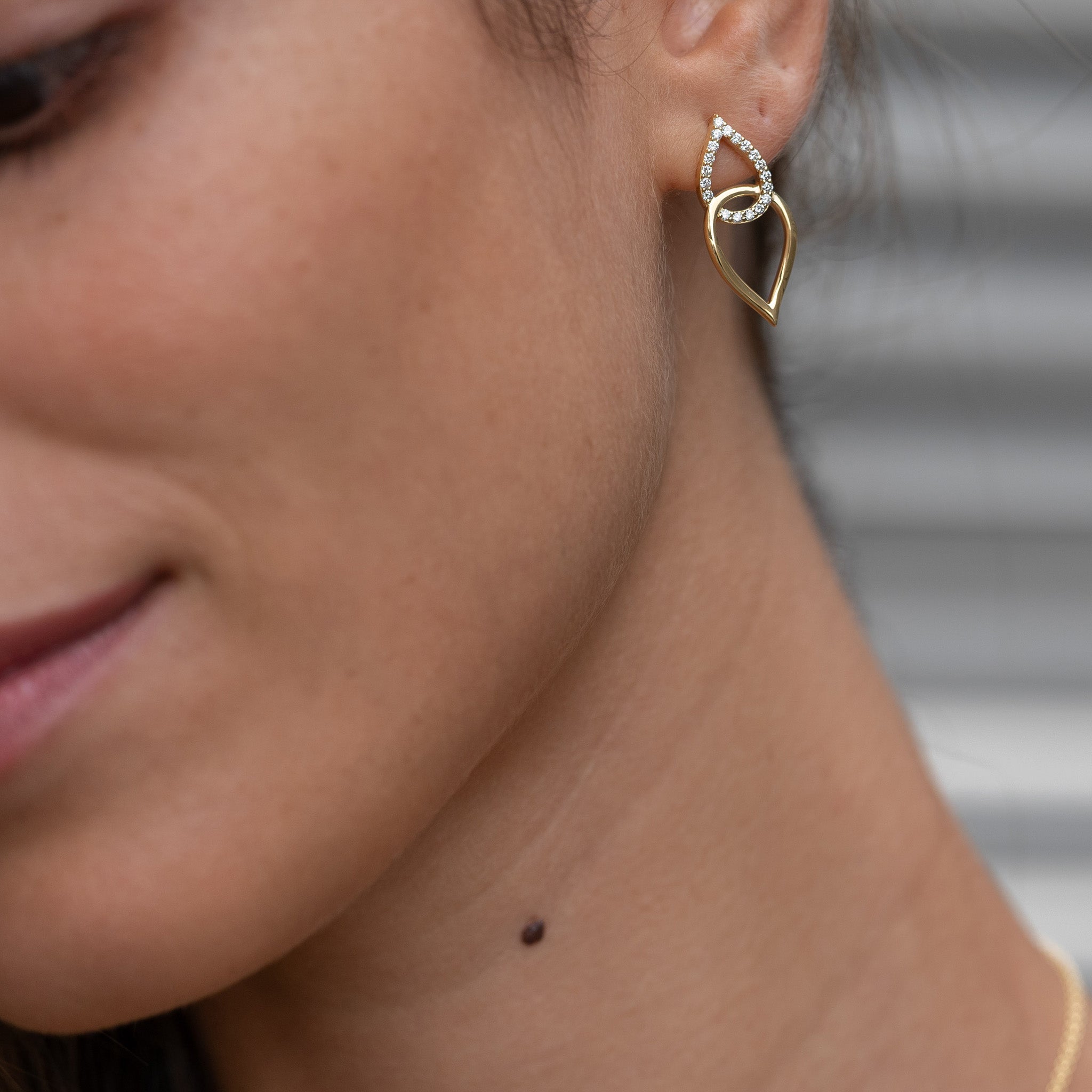 Yellow gold earrings inspired by sea knots, adorned with sparkling diamonds, showcased on model.