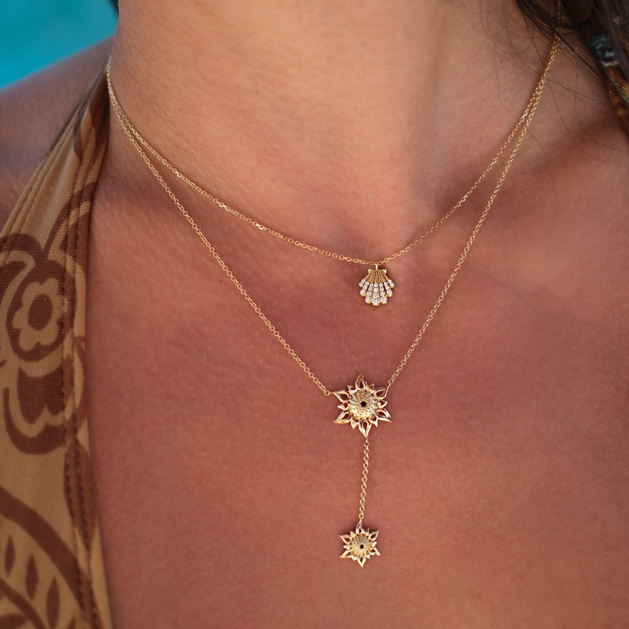 Gold necklace with star-shaped pendants on a person wearing a patterned top.