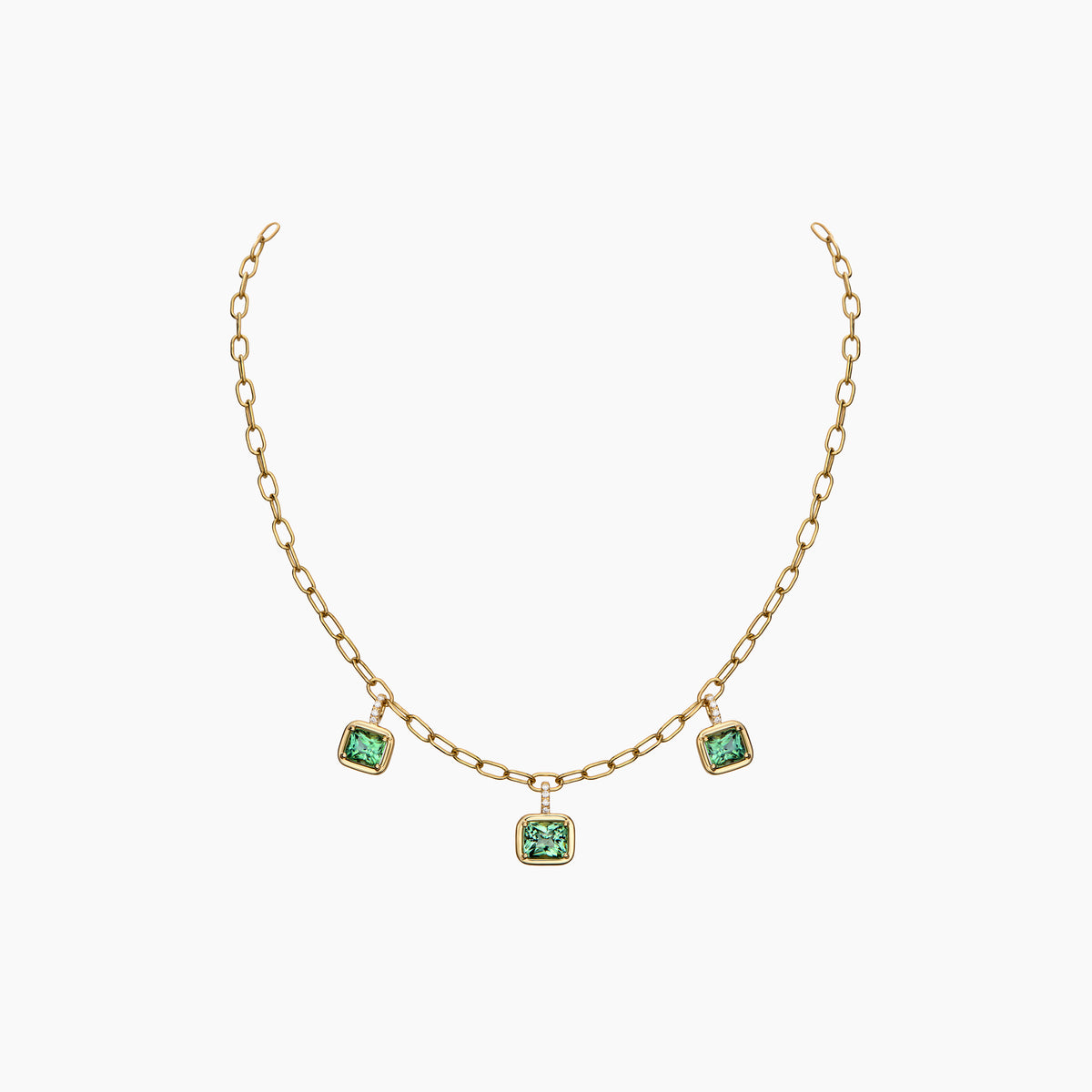 A gold chain necklace featuring three small square green gemstone charms, displayed against a clean white background.