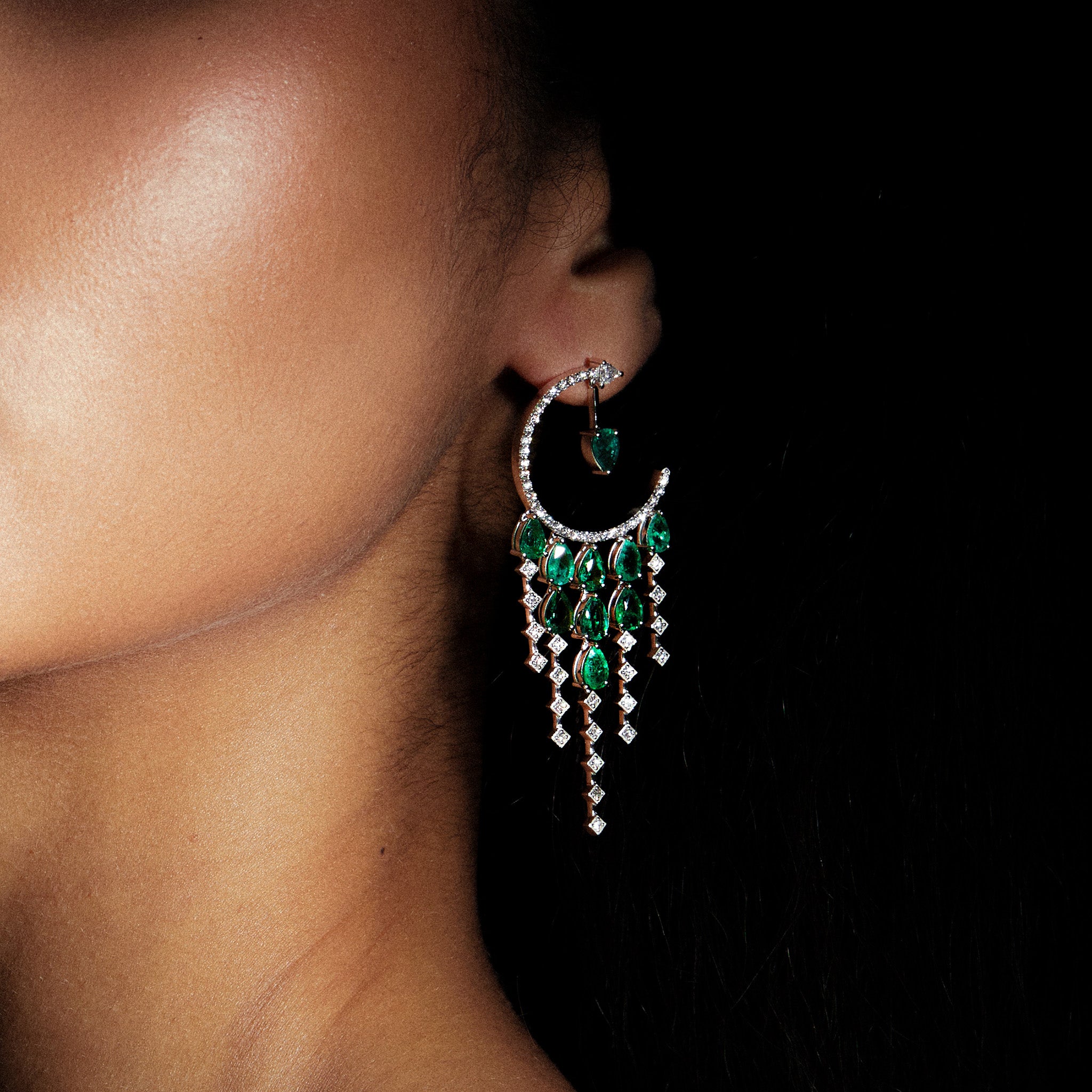 Anagenesis Emerald and Diamond Earrings, exquisite green emeralds and sparkling diamonds, showcased on model.