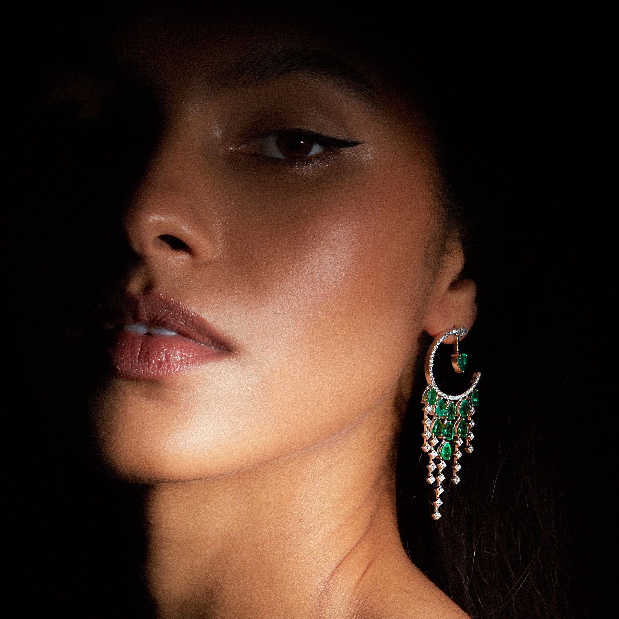 Anagenesis Emerald and Diamond Earrings, exquisite green emeralds and sparkling diamonds, showcased on model.