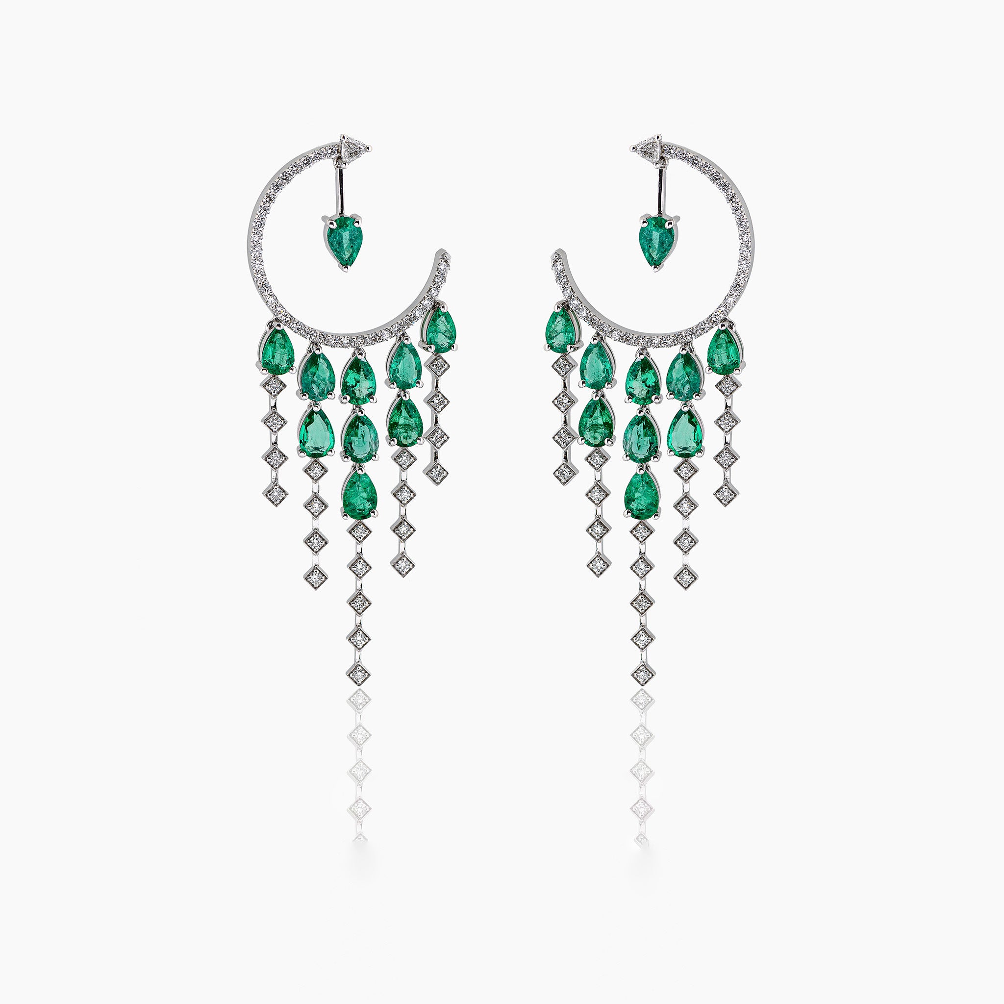 Anagenesis Emerald and Diamond Earrings, exquisite green emeralds and sparkling diamonds, showcased on an off-white background.