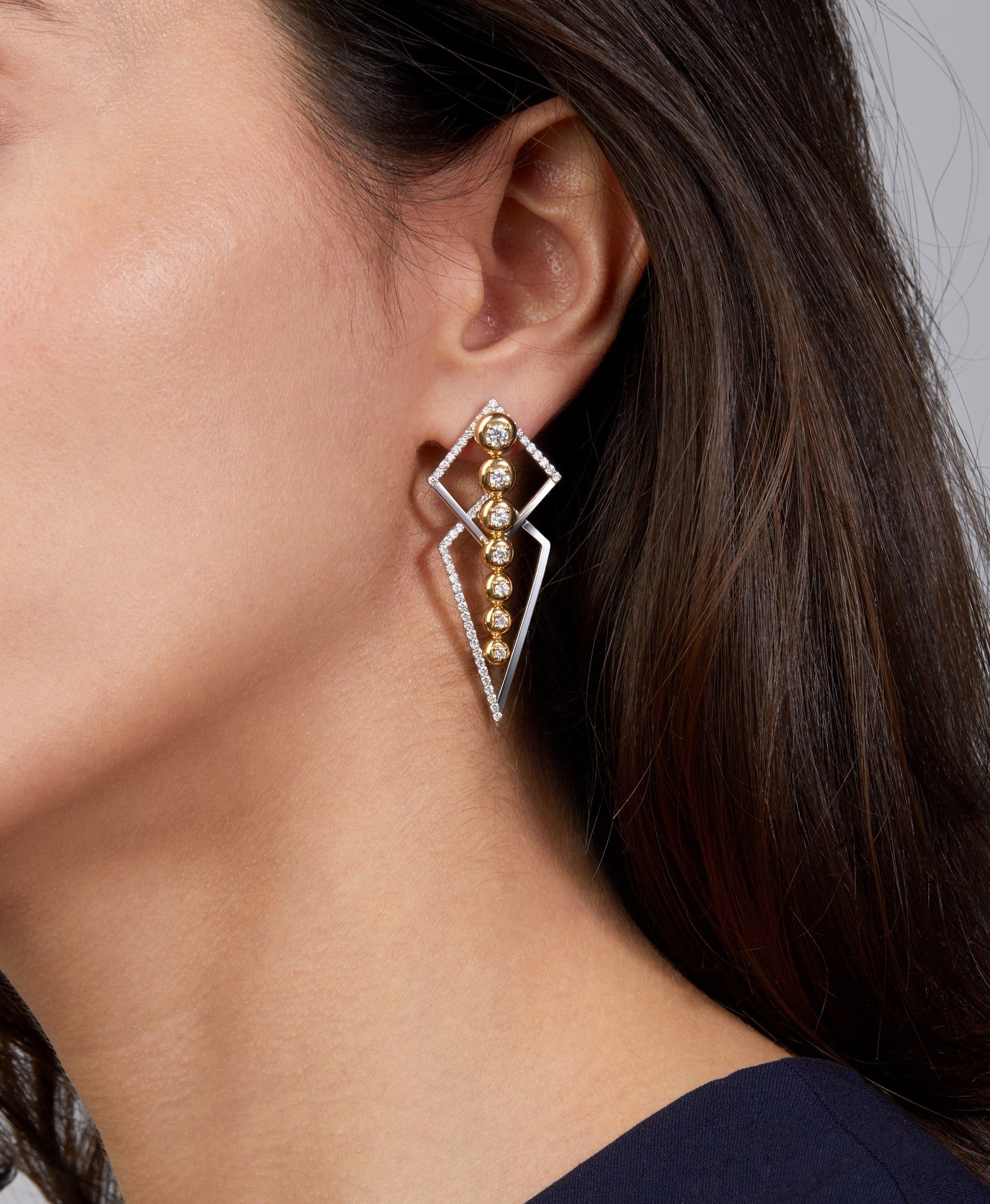 Two earrings combined in one in yellow and white gold displayed on model. 