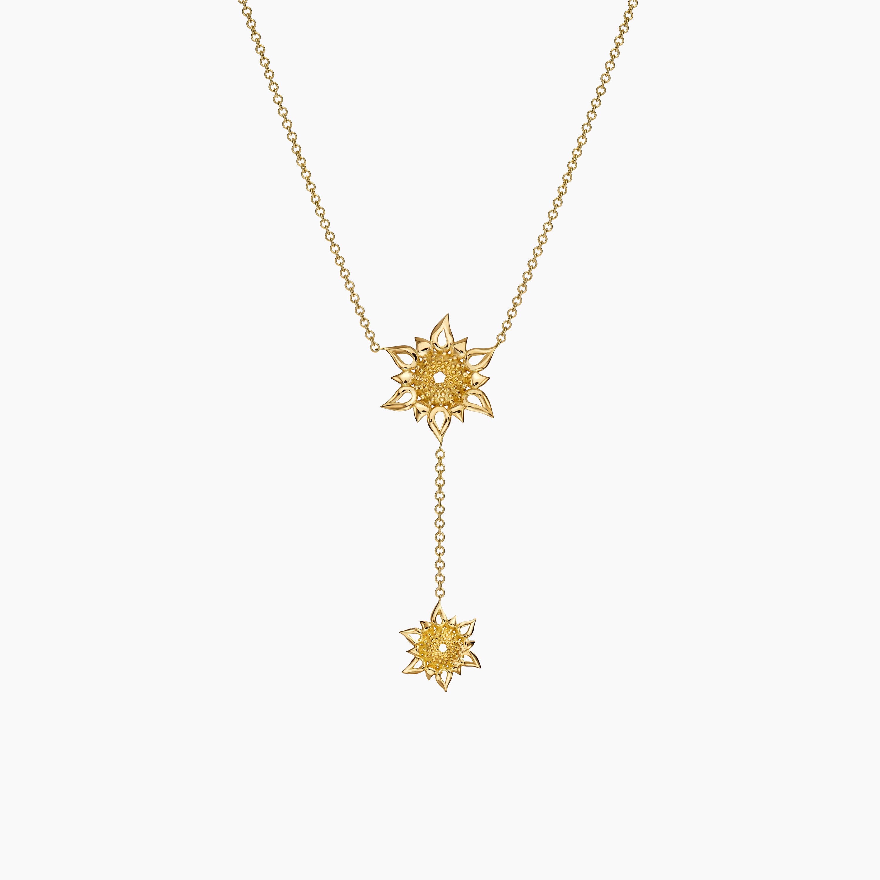 Gold necklace with sun charms 
on an off white background 