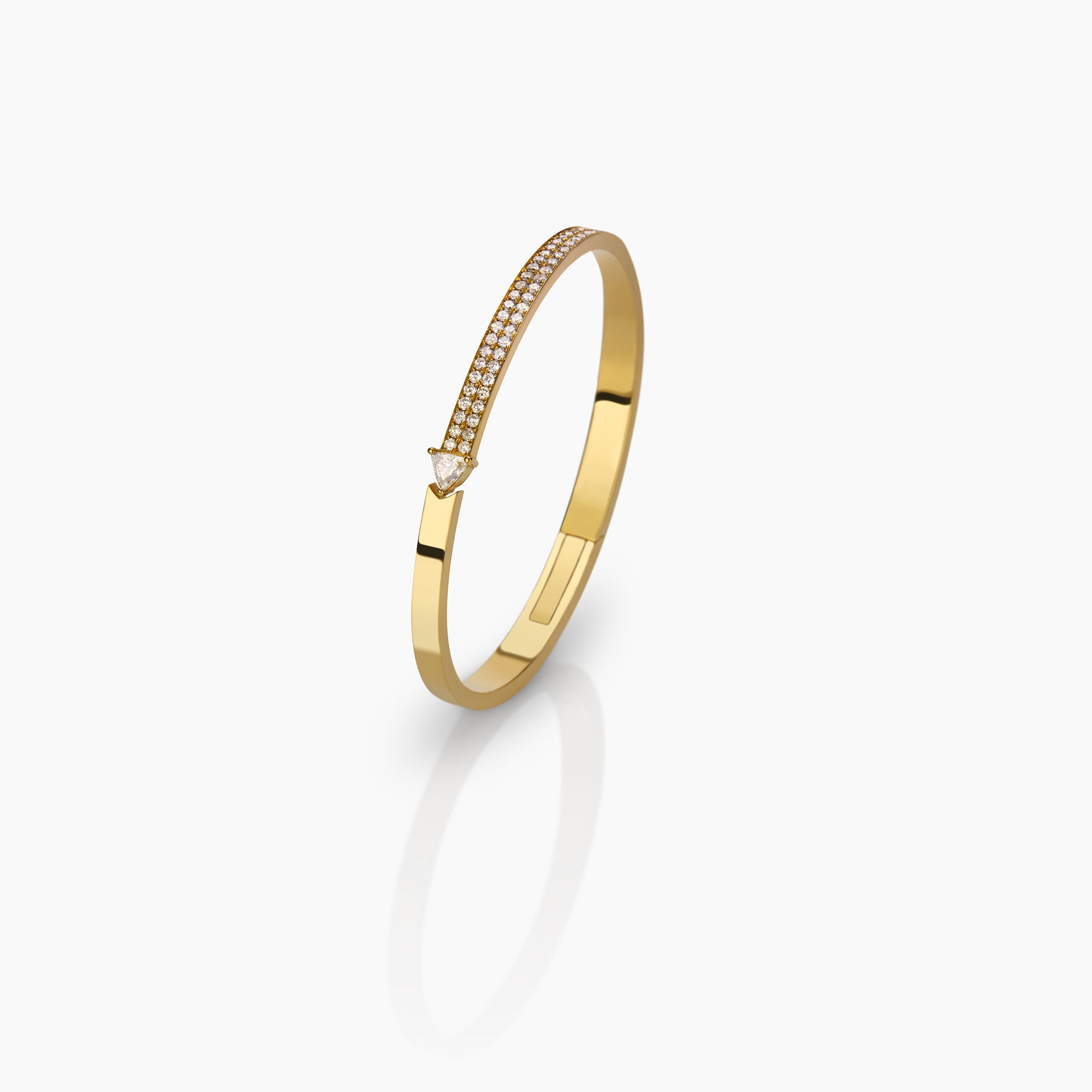 Yellow gold bangle with pave diamonds and a trillion displayed against an off white background