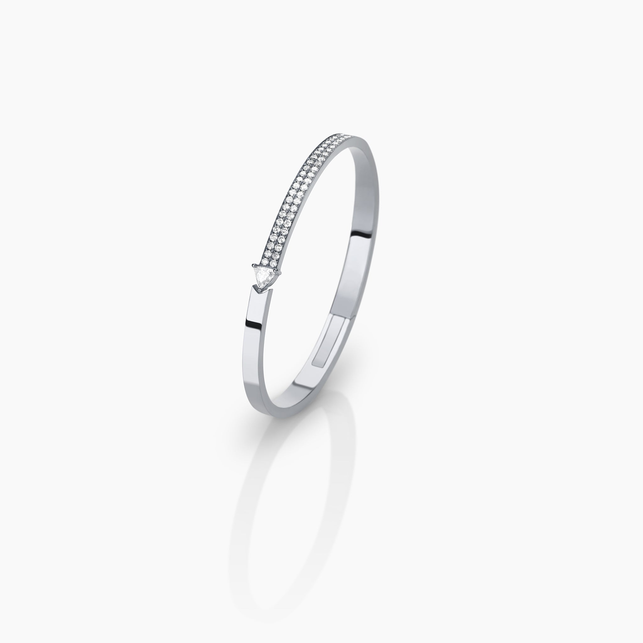 White gold bangle with diamonds set against an off white background