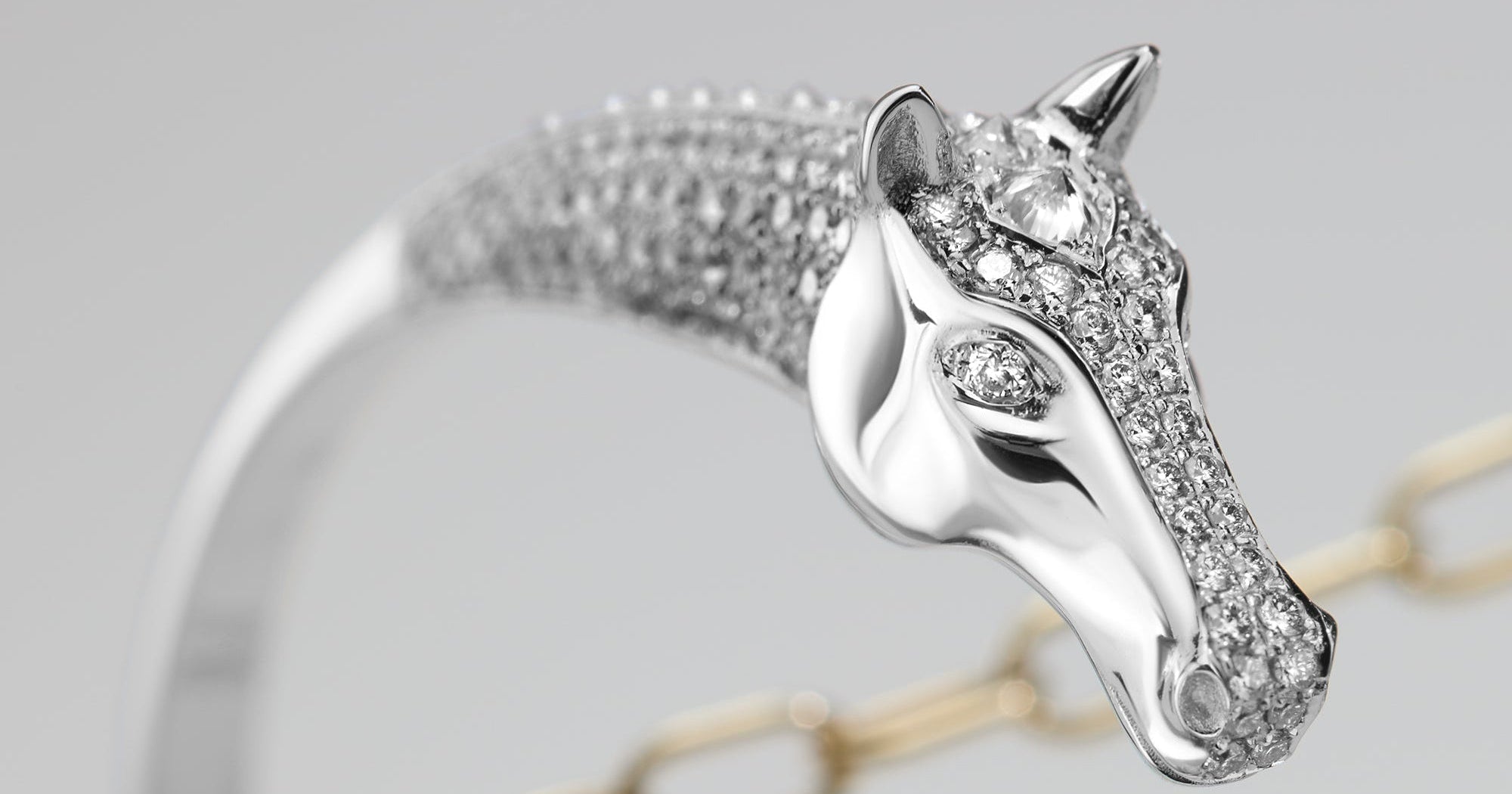 white gold horse head bracelet with diamond accents on a gray background