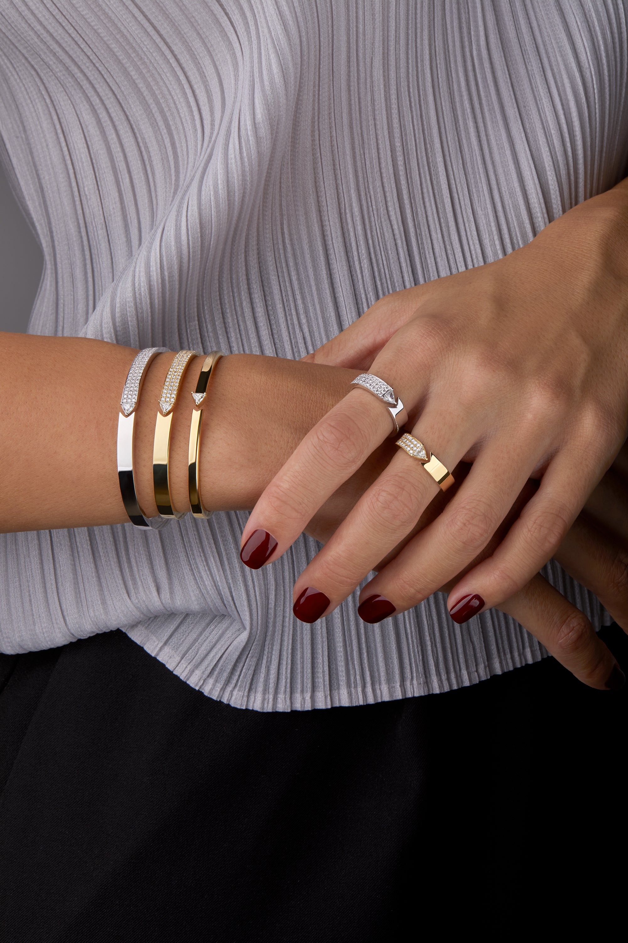 Stellar Standstill bangle and matching rings in yellow and white gold featuring diamonds  displayed on hand model. 