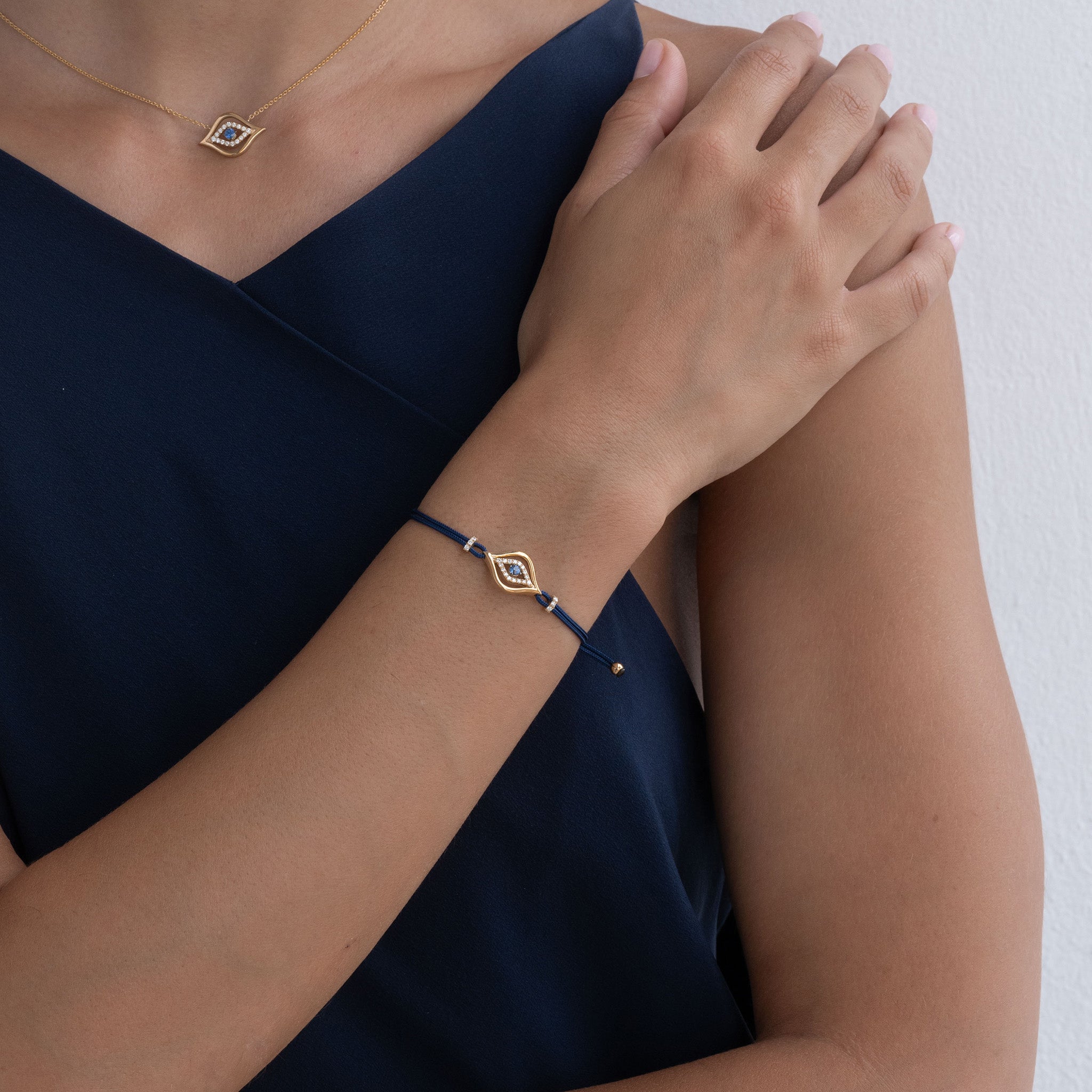 Model Wearing Evil Eye Pendant and bracelet: A model gracefully adorns the Yellow Gold Evil Eye Pendant with Diamonds and a round brilliant sapphire, radiating elegance and charm. 