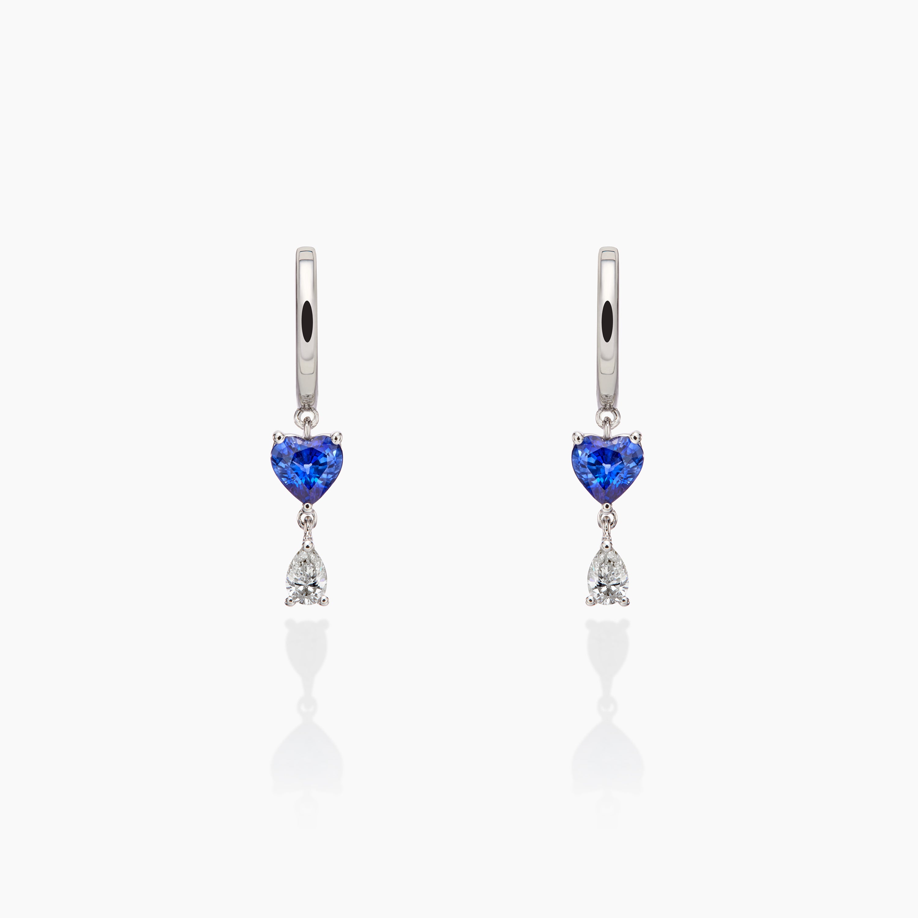 Sapphire and diamond earrings displayed agains an off white background 