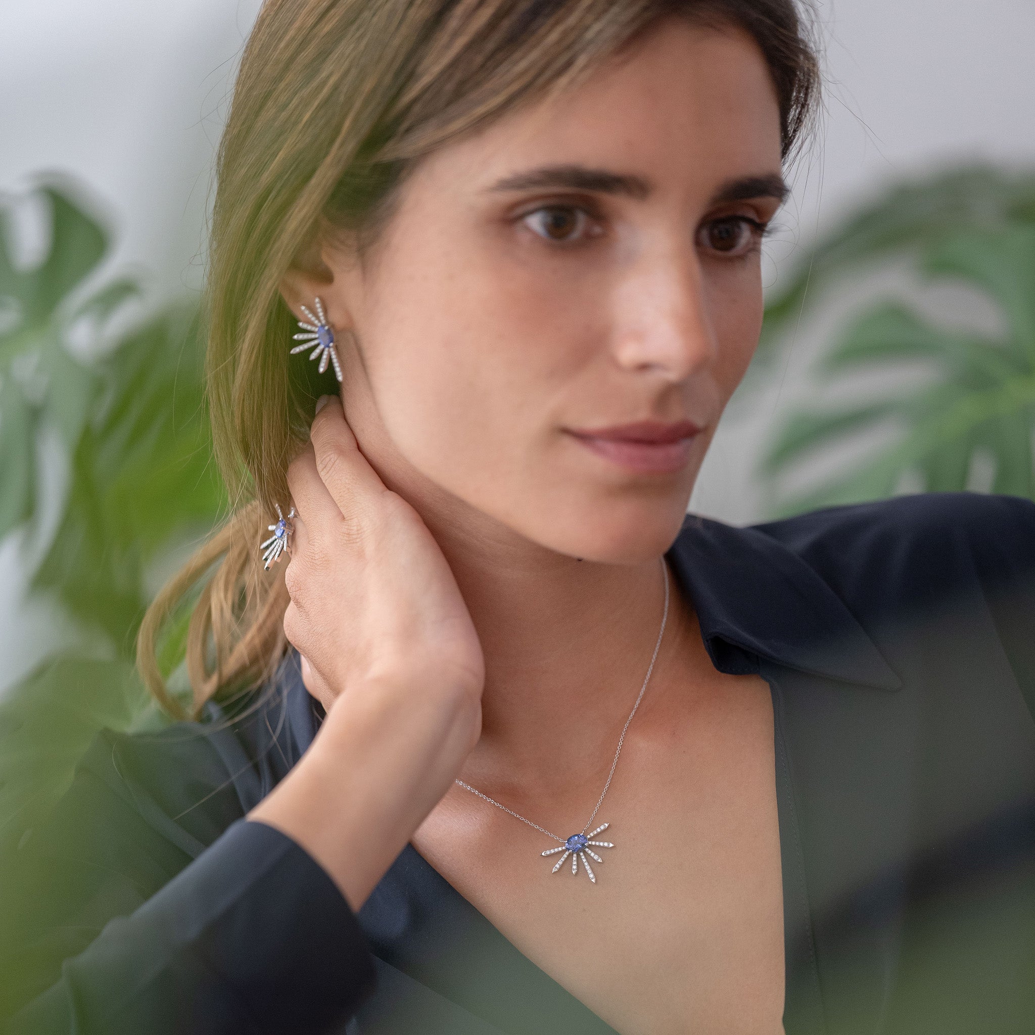 A breathtaking pendant, earrings and ring featuring a stunning Tanzanite center stone surrounded by dazzling diamonds displayed on model. 