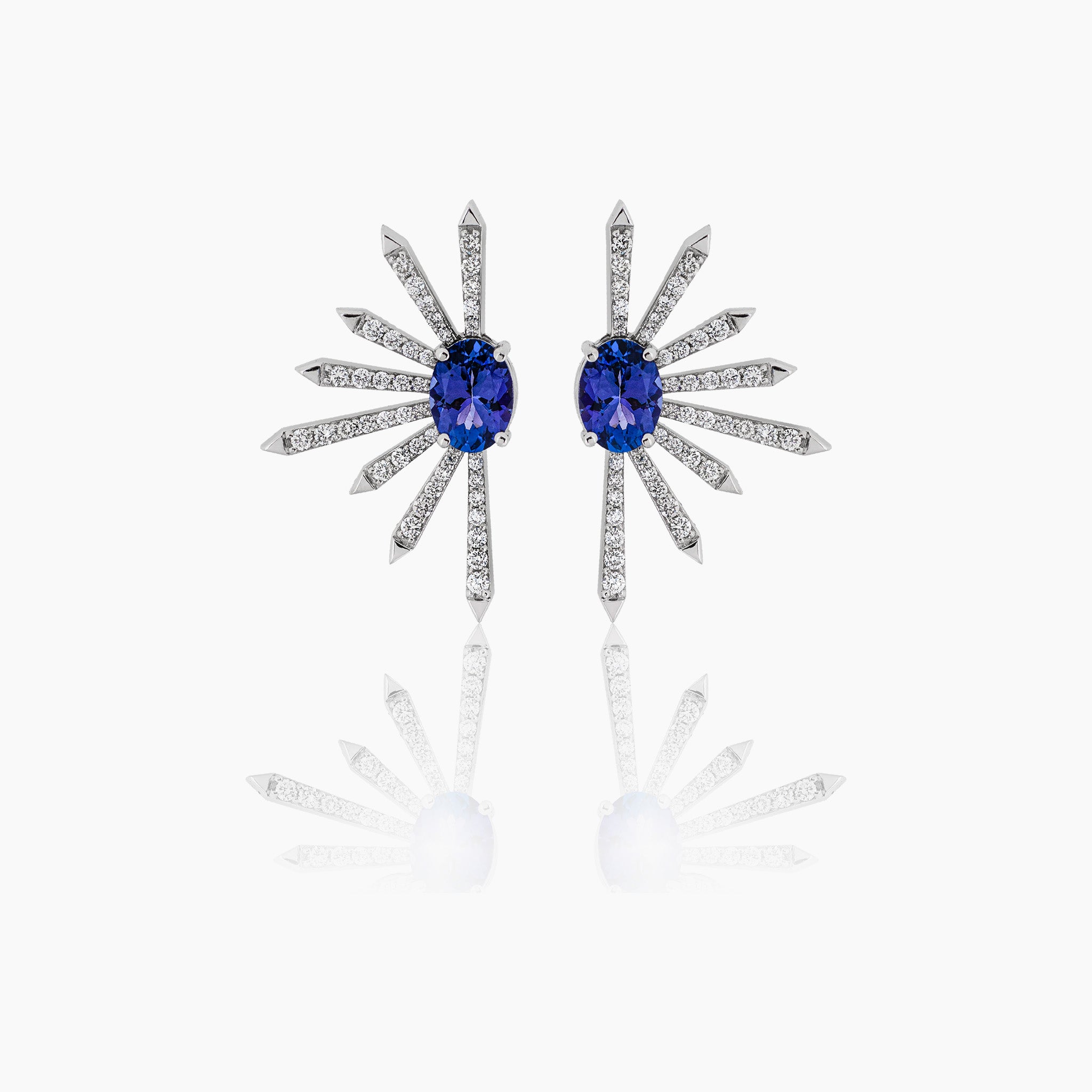 Diamond earrings with two elegant tanzanite ovals,  on an off-white background.