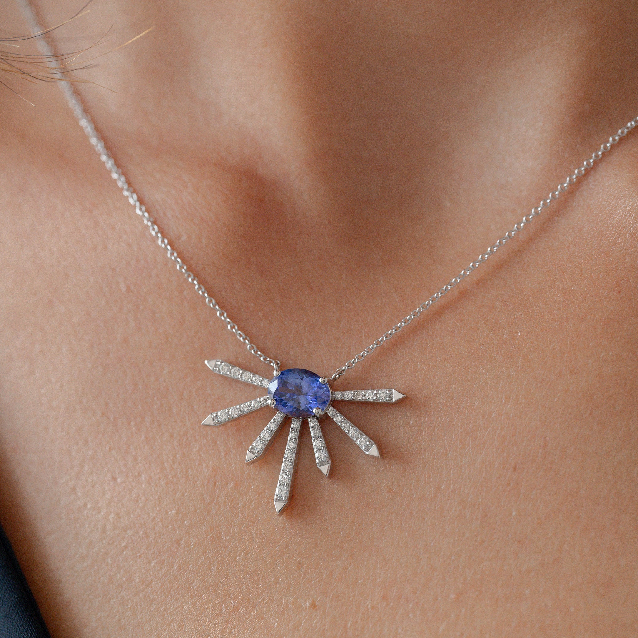 A breathtaking pendant featuring a stunning Tanzanite center stone surrounded by dazzling diamonds displayed on model. 