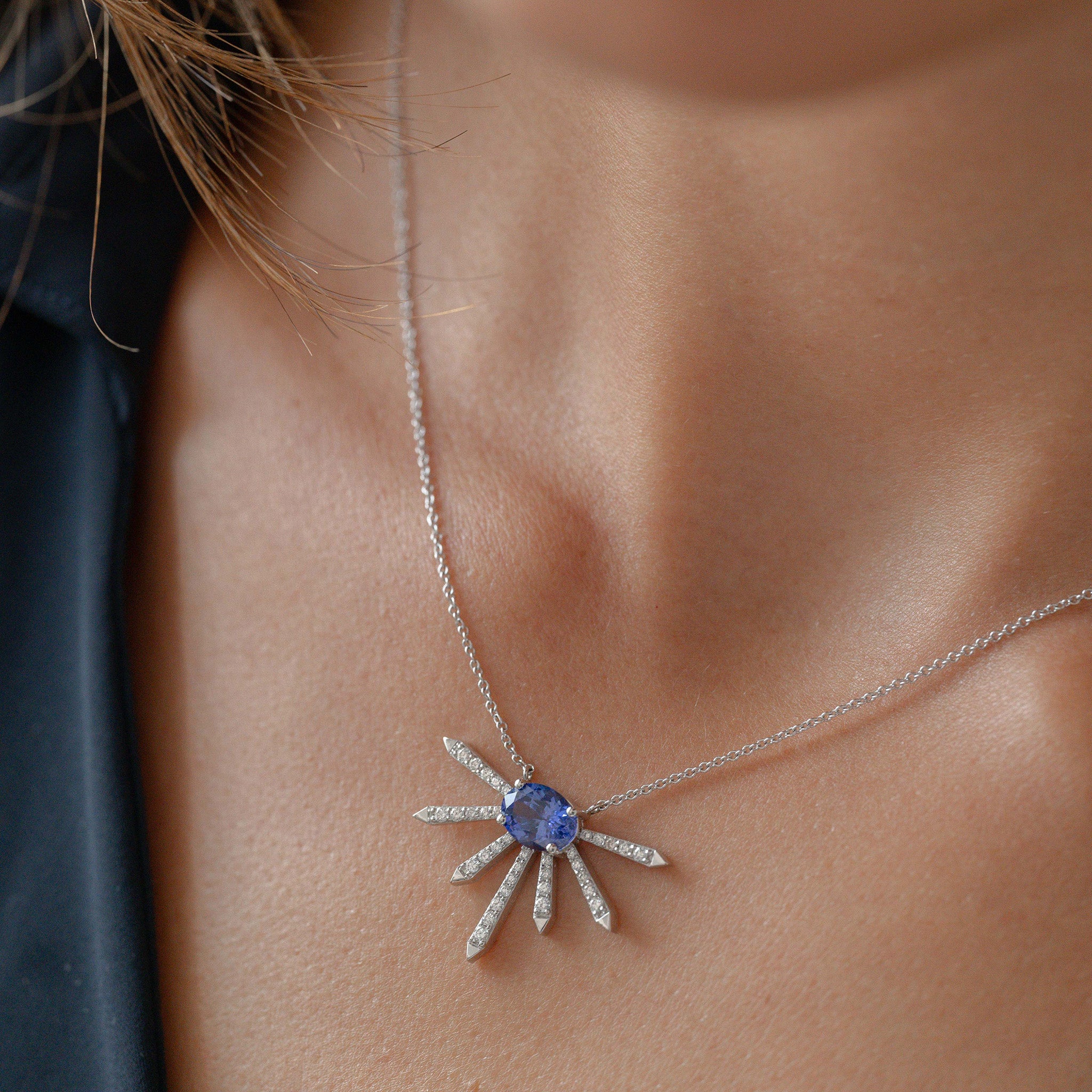 A breathtaking pendant featuring a stunning Tanzanite center stone surrounded by dazzling diamonds displayed on model. 