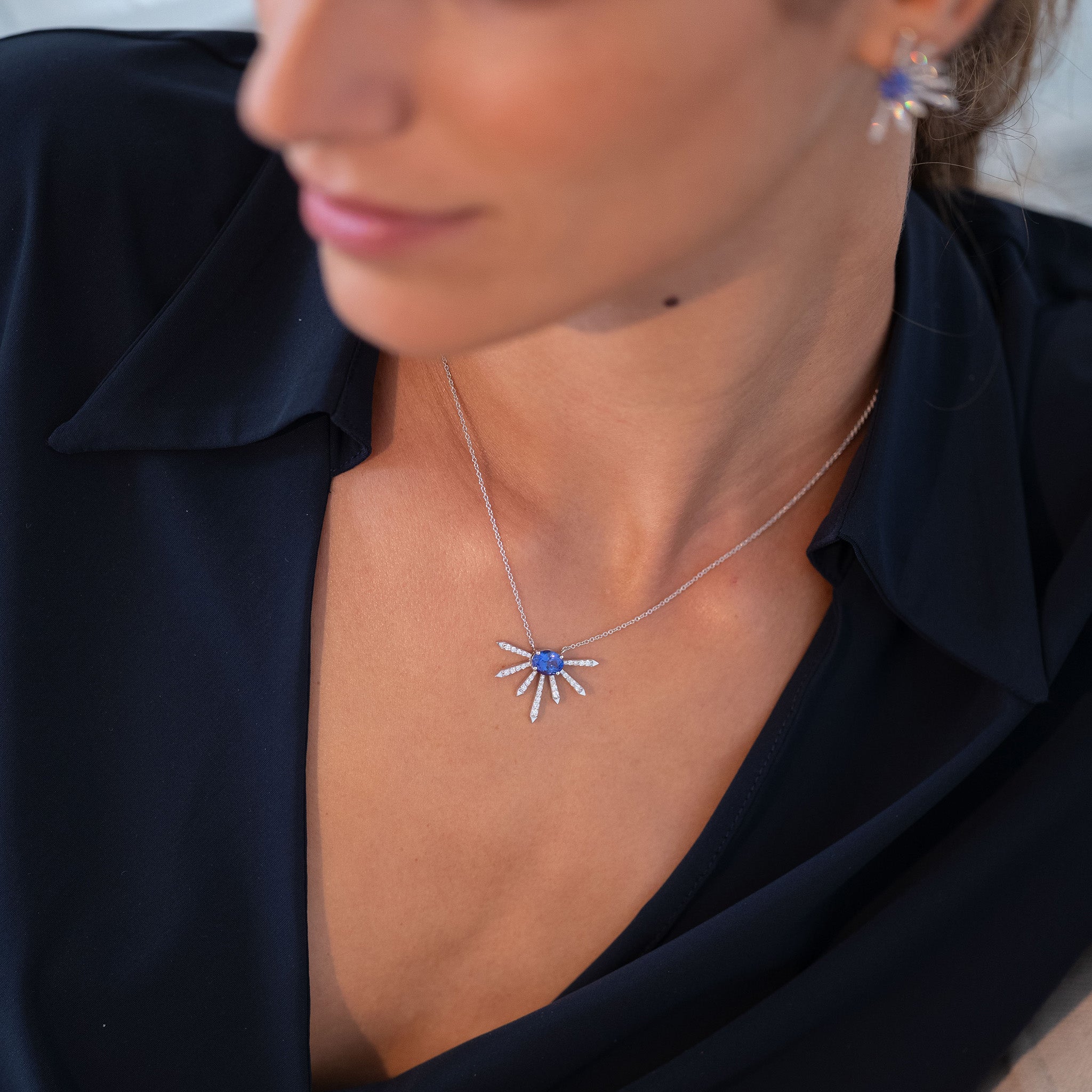 A breathtaking pendant featuring a stunning Tanzanite center stone surrounded by dazzling diamonds displayed on model. 