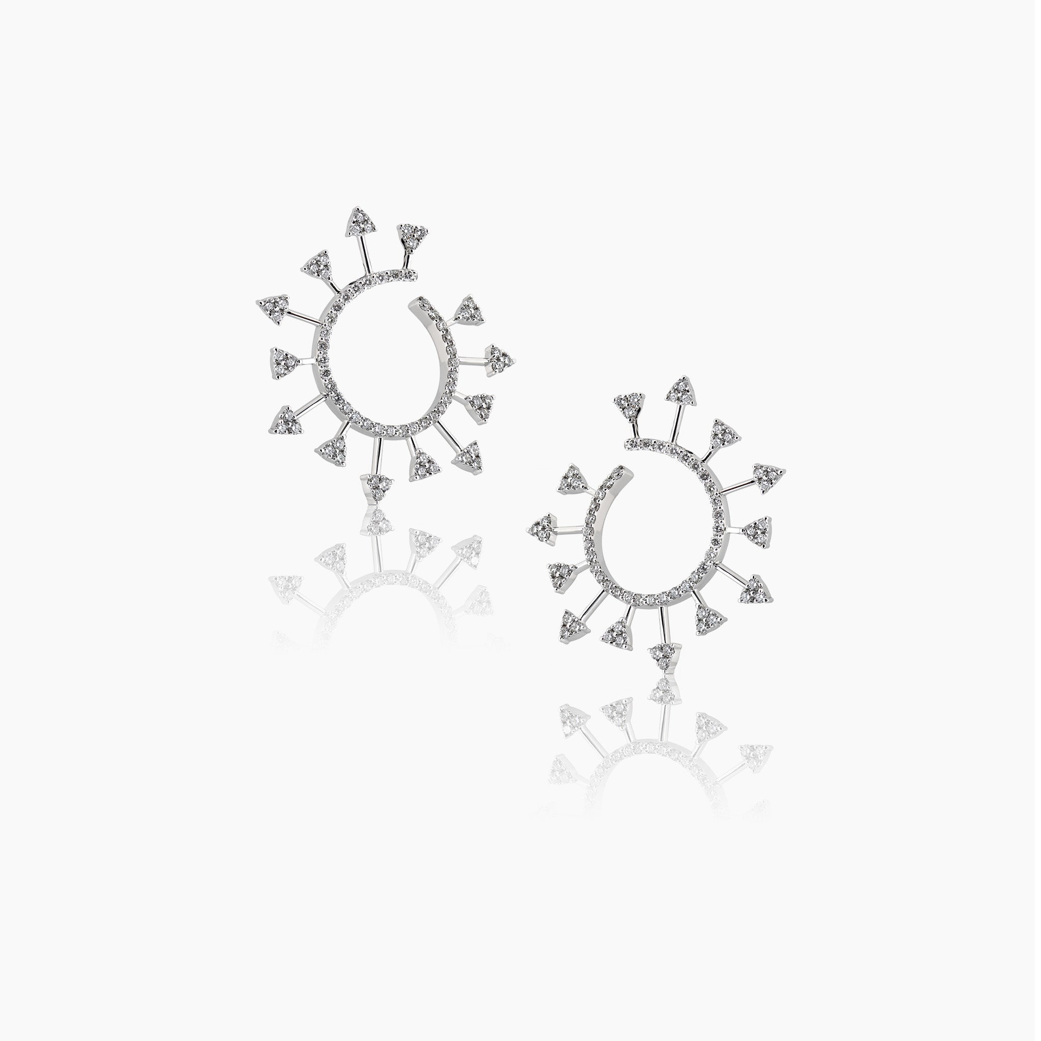 White gold diamond spiral earrings against a clean off-white background
