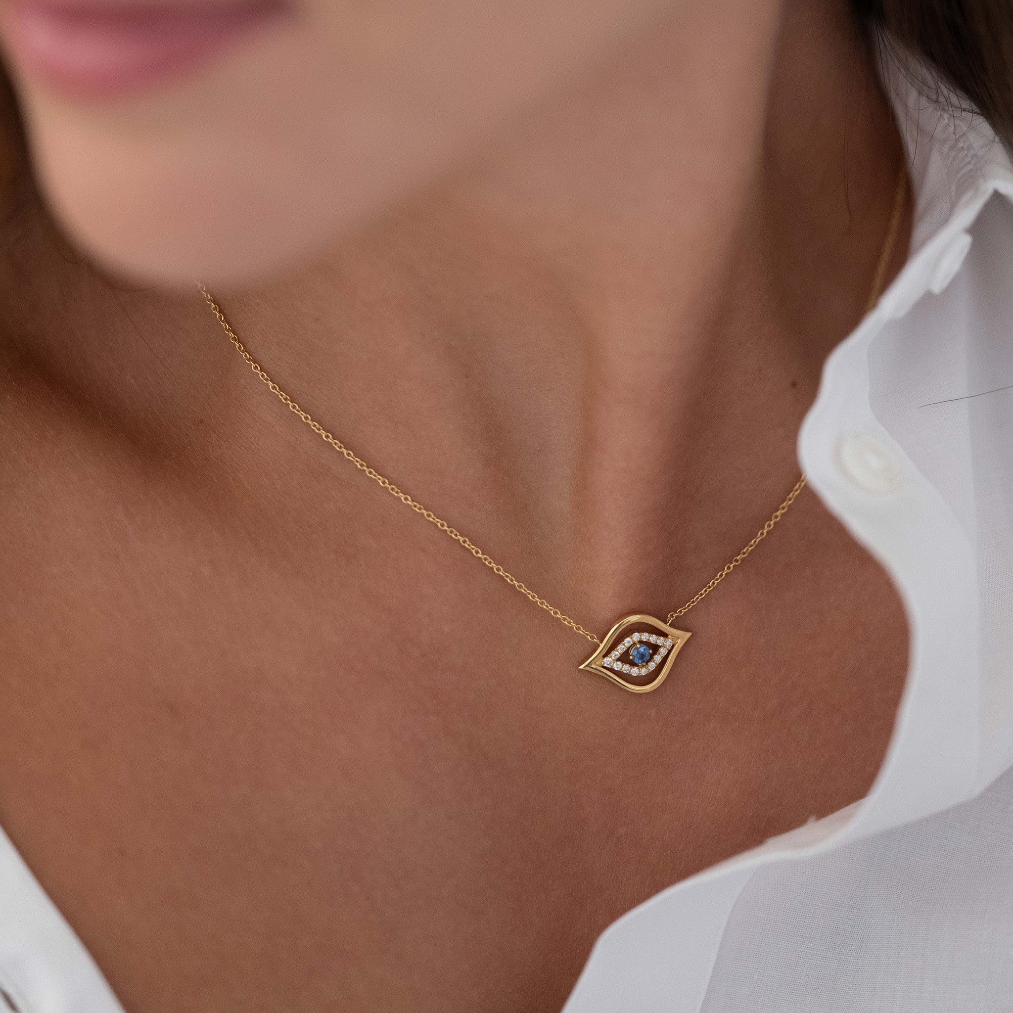 Model Wearing Evil Eye Pendant: A model gracefully adorns the Yellow Gold Evil Eye Pendant with Diamonds and a round brilliant sapphire, radiating elegance and charm. 