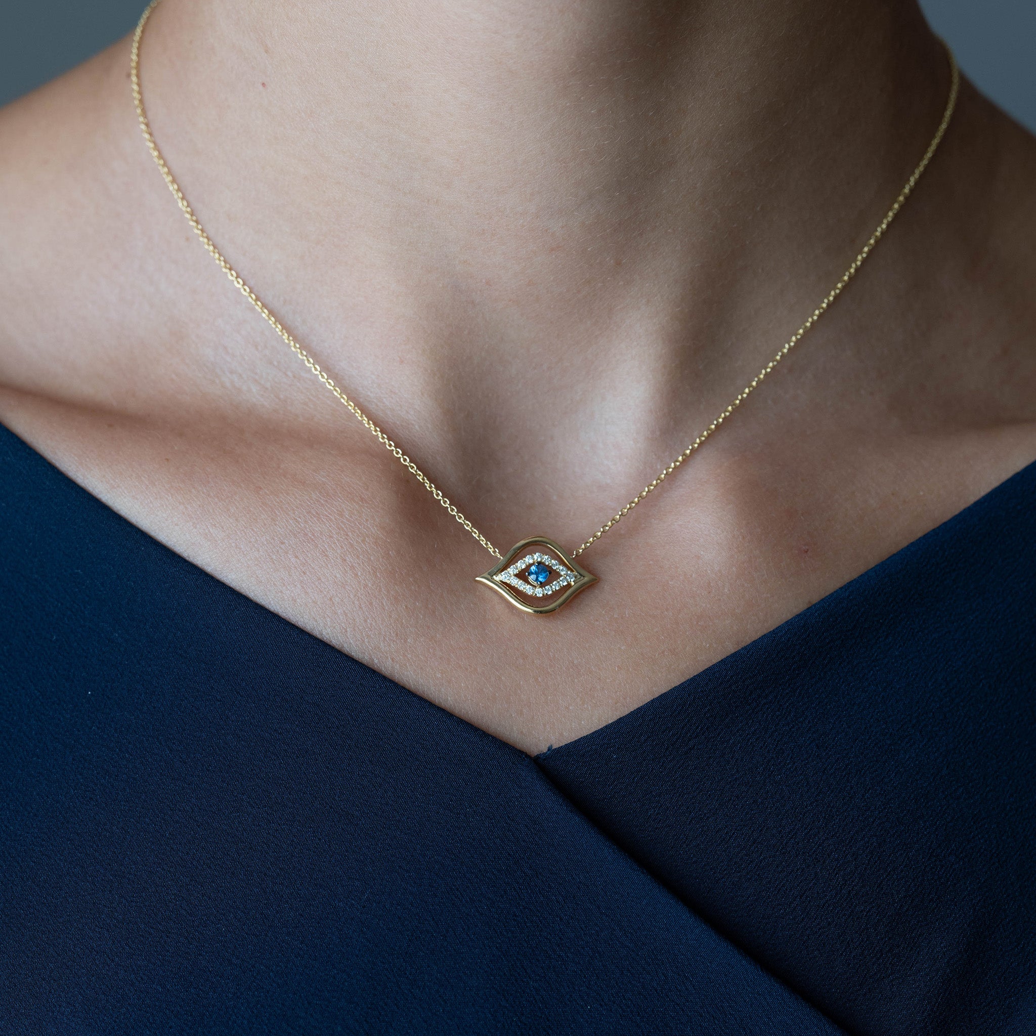 Model Wearing Evil Eye Pendant: A model gracefully adorns the Yellow Gold Evil Eye Pendant with Diamonds and a round brilliant sapphire, radiating elegance and charm. 
