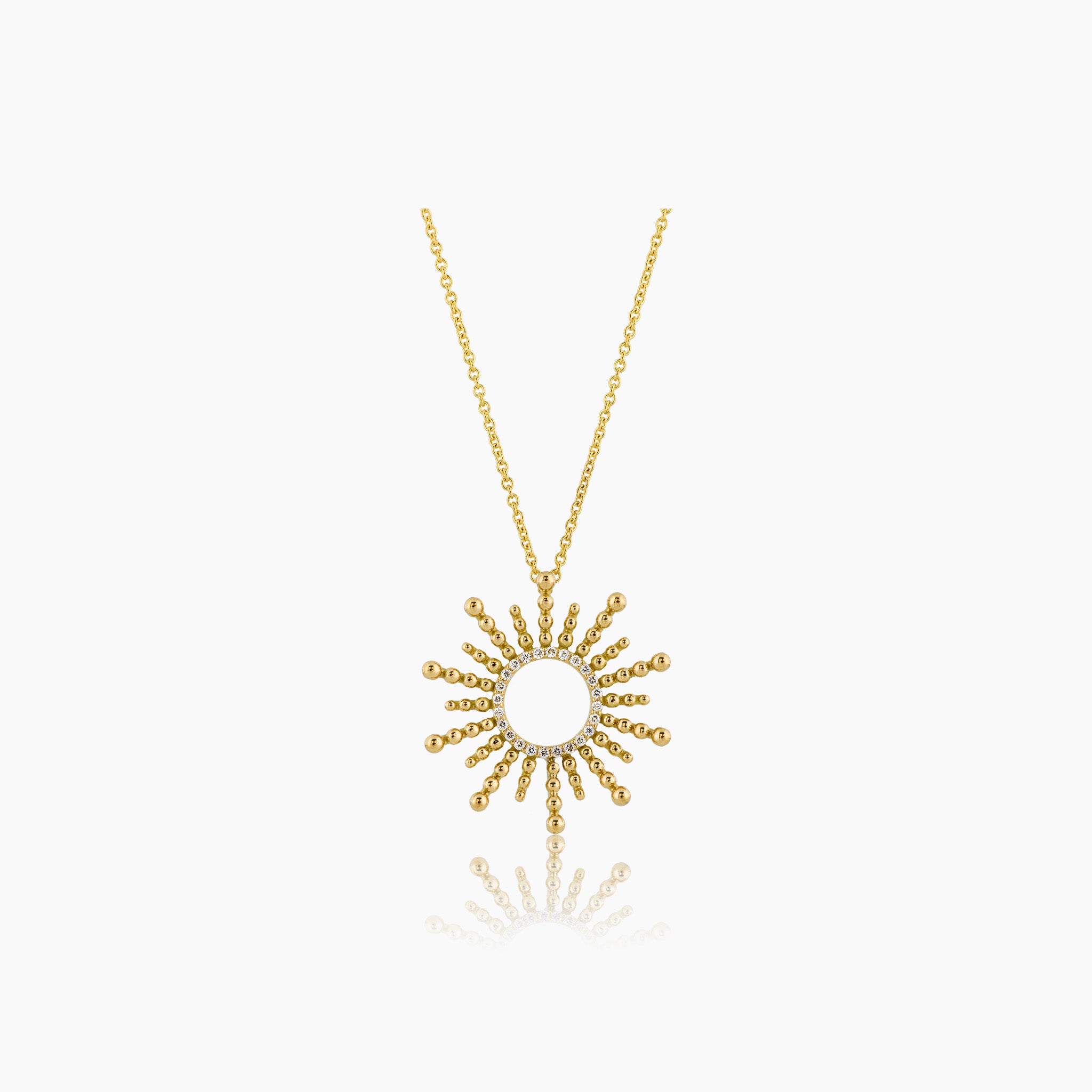 A beautifully crafted pendant made of gleaming yellow gold and diamonds, displayed elegantly on an off white background. 