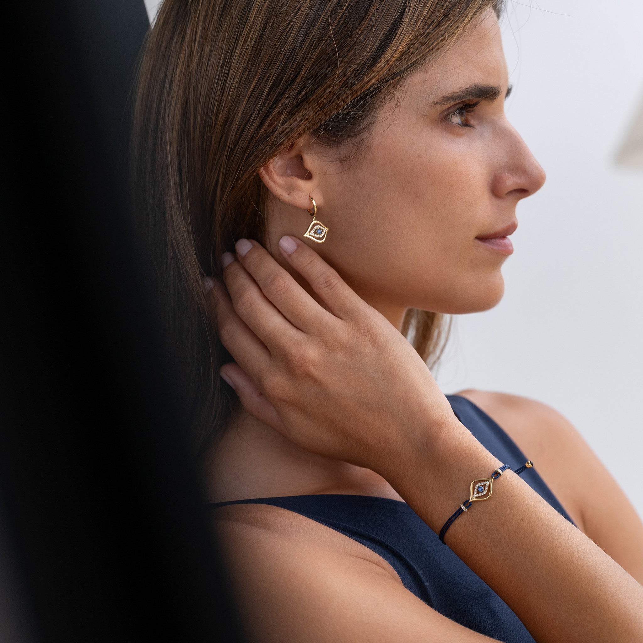 Exquisite fine jewellery featuring stunning diamond and sapphire earrings and evil eye bracelet on model.